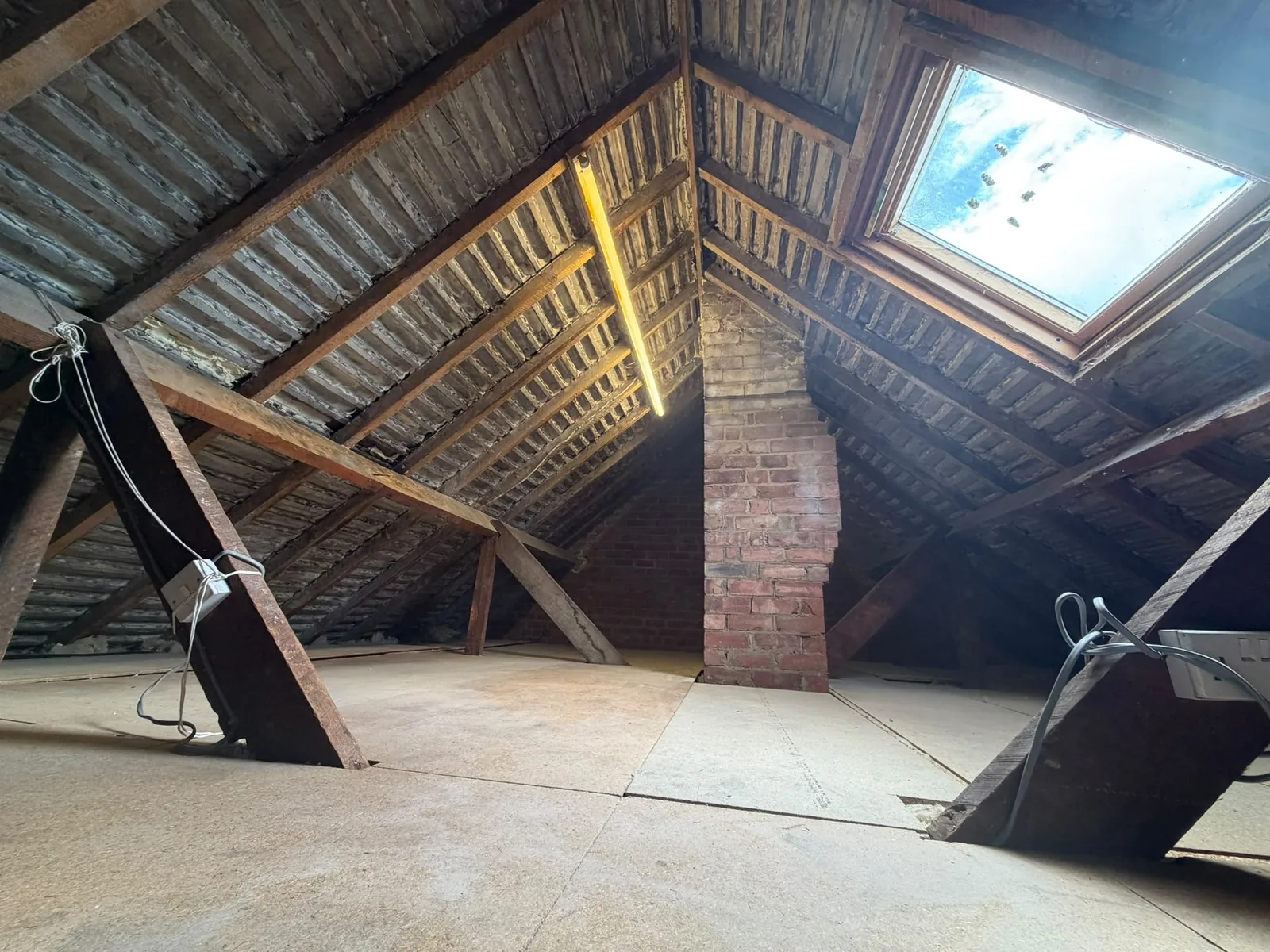 Boarded loft with clean rafters, lit by daylight from a roof window